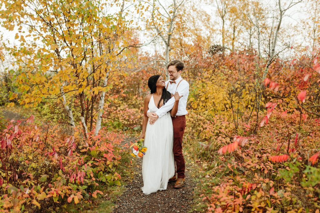 Bride and groom hugging in a mix of Fall leaves. 