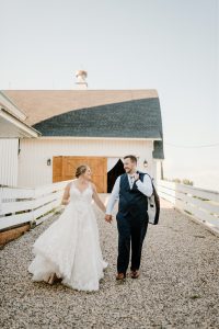 Bride and groom walking in front of barn