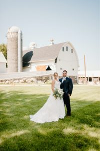 Bride and groom posing in front of barn