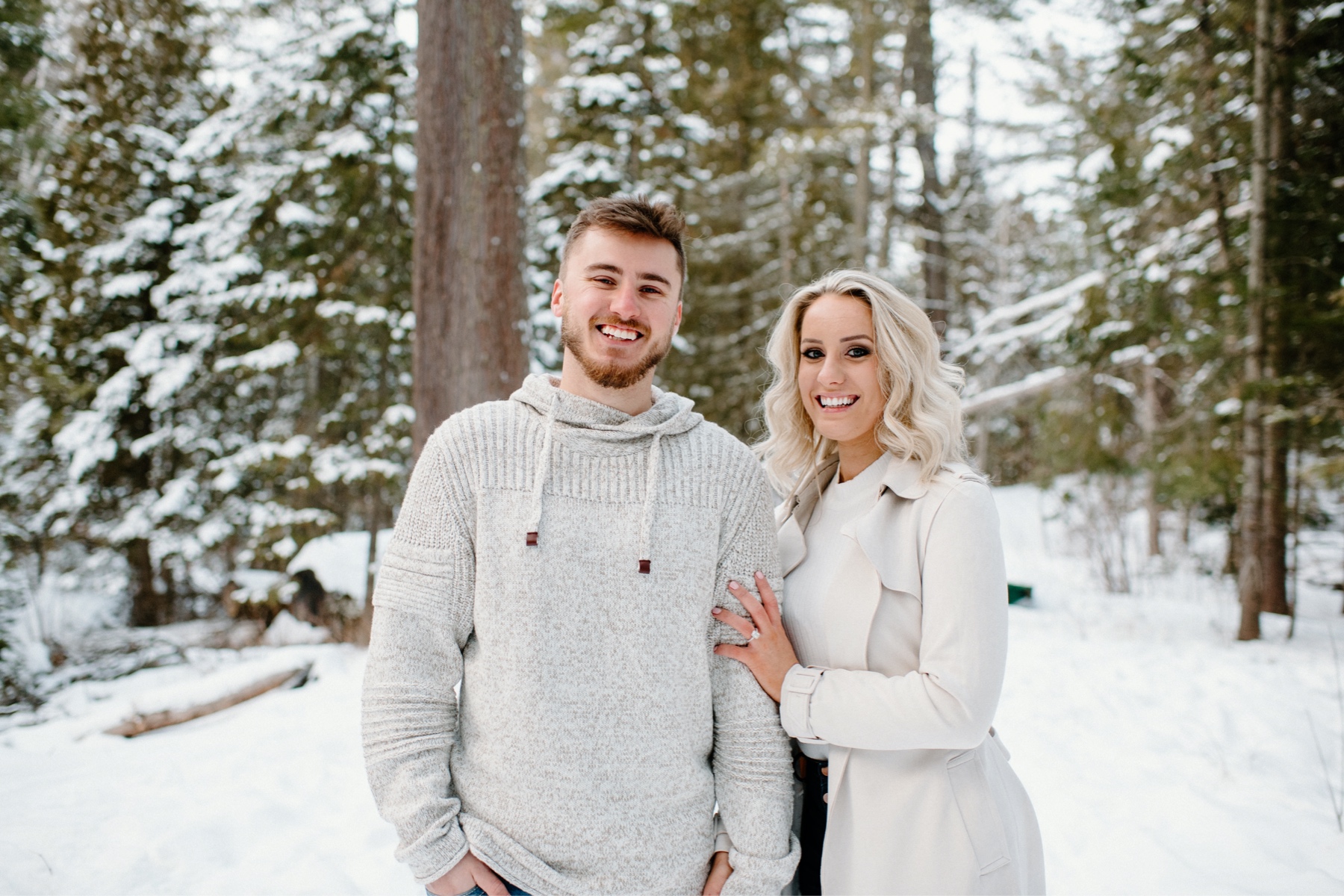 Couple posing in a snowy wooded area
